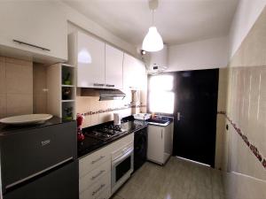 a small kitchen with white cabinets and a black refrigerator at rabatapartmentresidence in Rabat