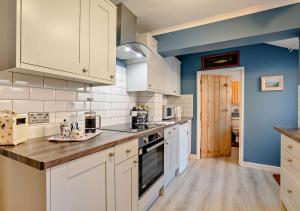 a kitchen with white cabinets and a blue wall at Bond Cottage in Overstrand