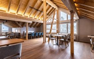 a restaurant with wooden ceilings and tables and chairs at Hotel Piz Badus in Andermatt