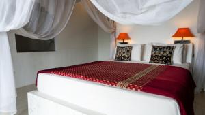 a white bedroom with a large bed with red sheets at Anda Amed Villas & Spa in Amed