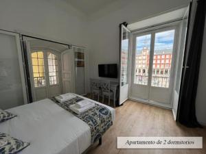 a bedroom with a bed and a desk and windows at Plaza Mayor in Madrid