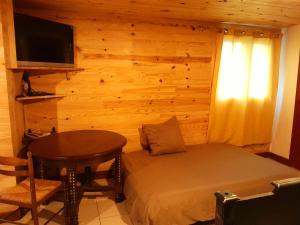 a bedroom with a bed and a table and a television at L'Auberge du Périgord in Truffe