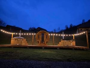 una casa de madera con luces encendidas por la noche en Biotour Camping & Restaurant en Ghimeş