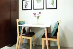 a table with two chairs and a vase with flowers on it at Fully-furnished Condo Accommodation in Makati in Manila