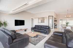 uma sala de estar com mobiliário de couro e uma televisão de ecrã plano em Seaside Villa em Bloubergstrand