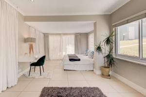 1 dormitorio con cama, escritorio y ventana en Seaside Villa, en Bloubergstrand