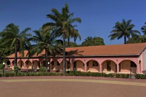 a pink building with palm trees in the background at Dunia Hôtel Bissau in Bissau