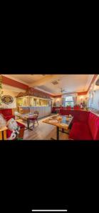 Neptunes Rest Guest Hotel في سترانراير: غرفة معيشة مع أريكة حمراء وطاولات