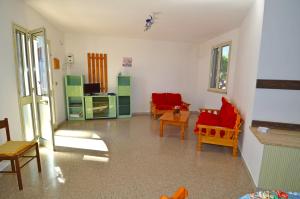 een woonkamer met rode stoelen en een keuken bij GINESTRA 3 in Marina di Pescoluse