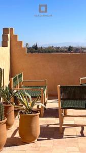 un groupe de bancs et de plantes en pot sur un patio dans l'établissement Villa Dar Hadjar, à Marrakech