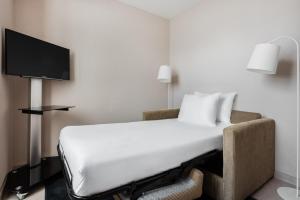 ein Hotelzimmer mit einem Bett und einem TV in der Unterkunft Exe Saldanha in Lissabon