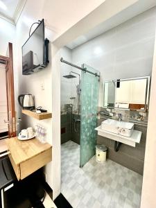 W łazience znajduje się szklana kabina prysznicowa i umywalka. w obiekcie Phụng Hoàng Vũ w mieście Bạc Liêu