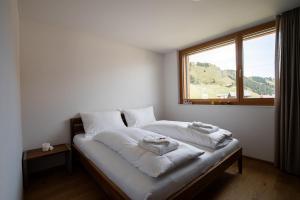 Schlafzimmer mit einem Bett mit weißer Bettwäsche und einem Fenster in der Unterkunft Alpenresort B22 in Riederalp