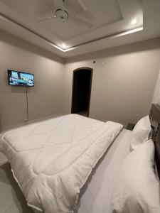 a bedroom with a white bed with a tv on the wall at Sunrise Residence in Islamabad