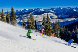 a group of people skiing down a snow covered slope at Charter at Beaver Creek E125 studio in Beaver Creek