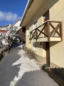 una acera cubierta de nieve junto a un edificio con balcón de madera en Chalupa Barbolica, en Vernár