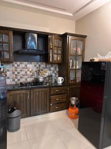 a kitchen with wooden cabinets and a black refrigerator at Sunrise Residence in Islamabad