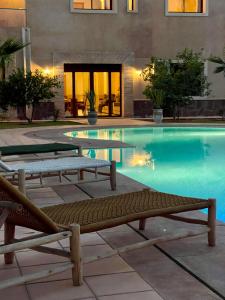 a swimming pool with two lounge chairs in front of a building at Villa Dar Hadjar in Marrakesh