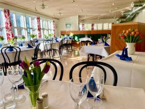 a dining room with white tables and chairs and flowers at STF Lillsved in Värmdö