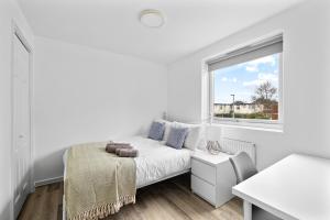 a white bedroom with a bed and a window at 20% OFF Spacious Cosy Home with Free Parking in Exeter