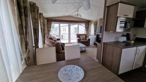 uma cozinha e sala de estar com uma mesa num quarto em Winchelsea Sands Holiday Park em Winchelsea