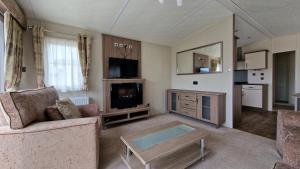 ein Wohnzimmer mit einem Sofa und einem TV in der Unterkunft Winchelsea Sands Holiday Park in Winchelsea