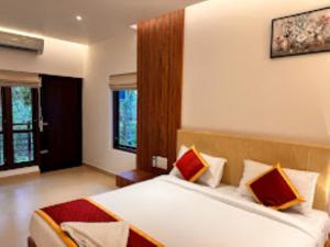 a bedroom with a large bed with red and orange pillows at Cliffotel Kerala in Chithragiri