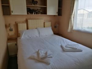 um quarto com uma cama branca e toalhas em Winchelsea Sands Holiday Park em Winchelsea