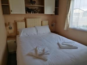 a bedroom with a white bed with towels on it at Winchelsea Sands Holiday Park in Winchelsea