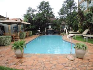 una piscina con fontana e cigni in un cortile di MACHAGE TOURS AND SAFARIS HOTEL a Karatu
