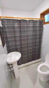 a bathroom with a toilet and a shower curtain at RGL Place Siargao in General Luna