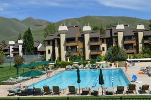 a hotel with a swimming pool with mountains in the background at Villager Condo 1203 - Newly Remodeled and Resort Amenities in Sun Valley