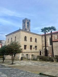un grand bâtiment avec une tour d'horloge et deux palmiers dans l'établissement Parada do Camiño de Santiago, à Betanzos