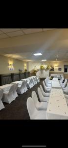 a room with white tables and white chairs at The Cotteridge Inn in Birmingham