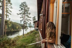 Una mujer mirando por la ventana de un tren en un río en Barken Lodge, en Smedjebacken
