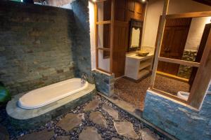een badkamer met een bad en een raam bij Bale D'Uma Joglo in Ubud