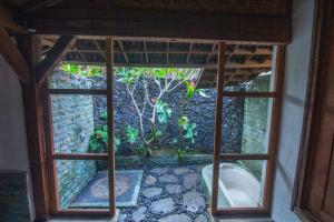 een raam met uitzicht op een tuin buiten bij Bale D'Uma Joglo in Ubud