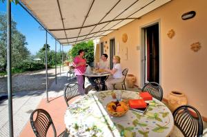 un groupe de personnes assises à une table sur un patio dans l'établissement Agriturismo Podere Zollaio, à Vinci