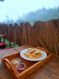 a plate with a sandwich and french fries on a wooden tray at Ella Nine Arch Glamp Site in Ella