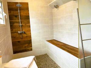 a bathroom with a tub and a shower with wood at Charme du Nord 1 in Sainte-Clotilde