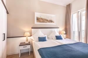 a bedroom with a large bed with blue and white sheets at Inselhuus Norderney in Norderney