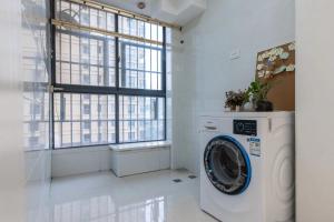 a washing machine in a room with a window at Huainan Aisen Elegant 2 Bedroom Residence Private Kitchen Elevator Secure Parking in Huainan +1 photo