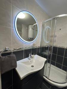 La salle de bains est pourvue d'un lavabo, d'un miroir et d'une douche. dans l'établissement Lumos, à Sombor