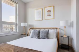 a white bedroom with a bed and two lamps at Brighton 2br w gym nr green line dining BOS-982 in Boston