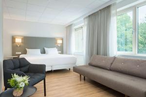 um quarto de hotel com uma cama e um sofá em NH Eindhoven Conference Centre Koningshof em Veldhoven