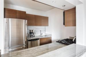 a kitchen with wooden cabinets and a stainless steel refrigerator at Midtown 1br w gym elevator nr Rockefeller Ctr NYC-1401 in New York