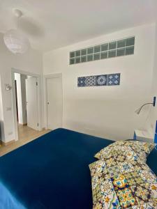 Un dormitorio con una cama azul y una pared blanca en Cuore d’Orlando apartment, en Capo dʼOrlando