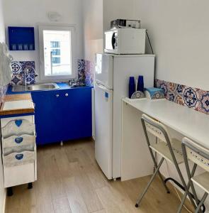 cocina con nevera blanca y armarios azules en Cuore d’Orlando apartment, en Capo dʼOrlando