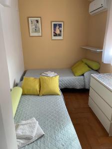 Camera piccola con 2 letti e cuscini gialli di Familia anfitriona acoge a Siviglia