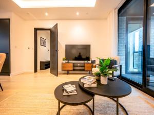 uma sala de estar com uma mesa e uma televisão em Pass the Keys Modern Exuberance and Luxury at Lucent House em Londres